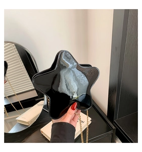 Détail du sac étoile en cuir verni noir brillant avec une bandoulière chaîne dorée