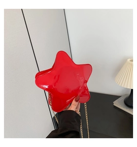 Détail du sac bandoulière étoile rouge en cuir verni brillant avec chaîne dorée
