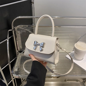 Chic cream-white crossbody handbag with silver metal bow accent and top handle