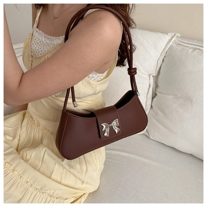 Detail of vintage brown leather shoulder bag with a silver metal bow accent and knotted strap