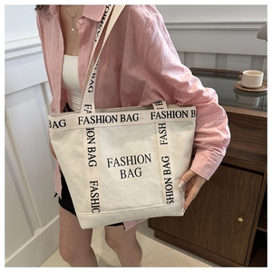 Detail of large canvas tote bag showing FASHION BAG lettering and shoulder strap texture