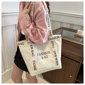 Close-up of cream canvas tote bag with black FASHION BAG text and sturdy shoulder straps