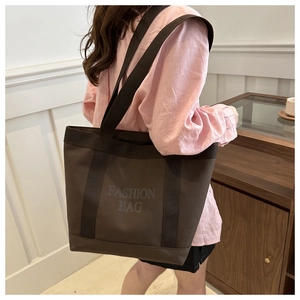 Close-up of wide shoulder strap and 'FASHION BAG' print on dark brown canvas tote bag