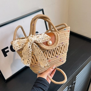 Sac à main en paille d'été avec nœud en dentelle et bouton perle en vue élégante à la main