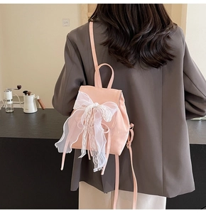 Gros plan d'un mini sac à dos rose avec un nœud en dentelle blanche et fines bretelles