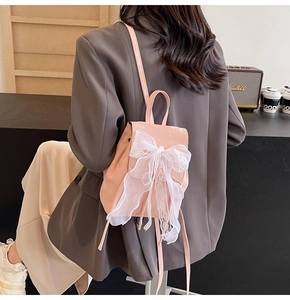 Vue détaillée d'un sac à dos en cuir rose avec un grand nœud en dentelle