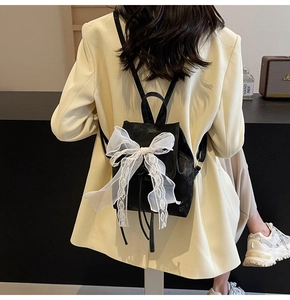Vue arrière d'un mannequin portant un sac à dos en cuir noir avec un grand nœud en dentelle