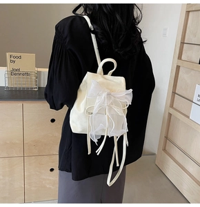 Détail d'un sac à dos en cuir blanc crème orné d'un grand nœud en tulle délicat au dos