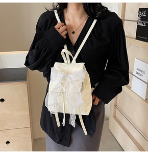 Détail du mini sac à dos crème avec grand nœud en dentelle et fermeture à cordon flap