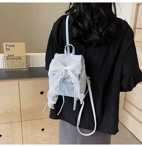 Vue arrière d'un mini sac à dos bleu clair avec un grand nœud en dentelle blanche