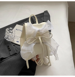Détail du mini sac à dos crème avec un grand nœud en dentelle et une poignée chic
