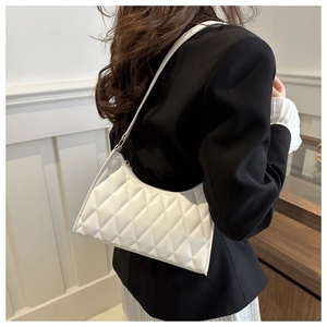 Détail du motif à losanges blancs sur le sac sous l'aisselle porté avec un blazer noir