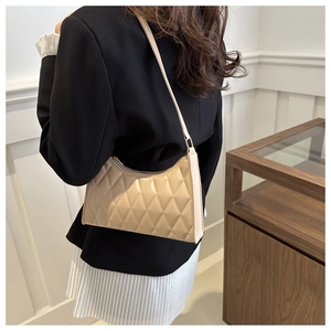 Détail du sac porté épaule matelassé abricot avec texture cuir brillant et coutures élégantes