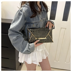 Chic black envelope clutch with gold metal buckle and crocodile texture held by model