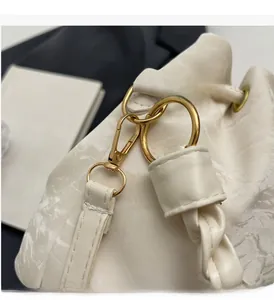 Detail of creamy white bucket bag featuring pleated texture and gold hardware accents