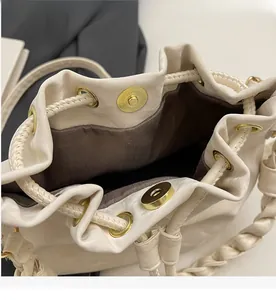 Close-up of golden magnetic closure and woven strap on a cream bucket bag