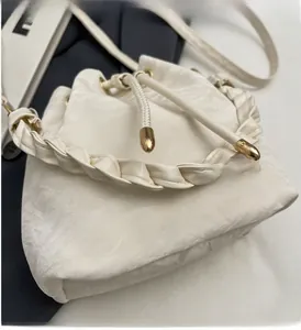 Detail of woven handle and metal drawstring tips on white bucket bag