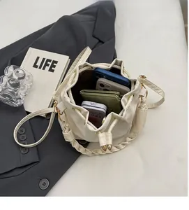 Top view of cream drawstring bucket bag showing spacious interior with phones and wallet