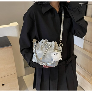 Detail of silver drawstring bucket bag with metallic crinkle texture and plush charm
