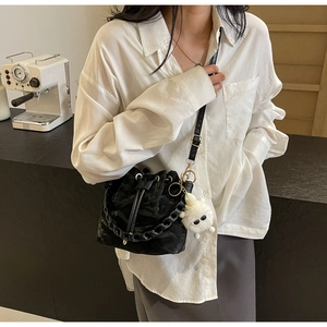 Detail of black drawstring bucket bag with textured finish and cute plush charm