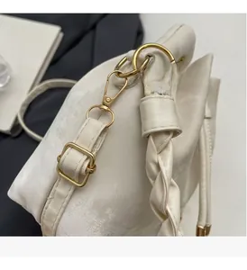 Close-up of golden hardware and woven strap on a cream drawstring bucket bag