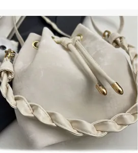 Close-up of beige suede bucket bag showing drawstring closure and woven handle detail