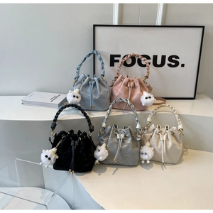 Detail of drawstring bucket bags in pastel colors with woven handles and plush charms