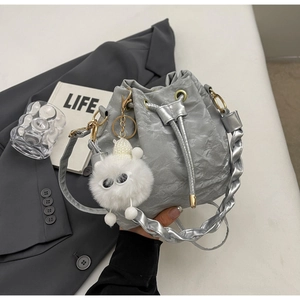 Detail of silver pleated bucket bag with braided strap and plush monster charm