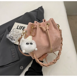 Pink drawstring bucket bag with textured fabric, woven handle, and cute plush charm