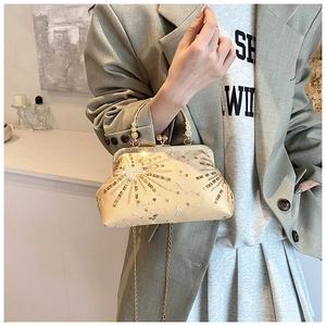 Detailed view of champagne sequin clutch bag with vintage metal frame and handle
