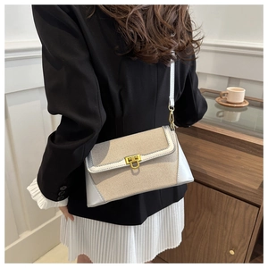 Detail of a chic crossbody bag featuring a golden lock and beige textured fabric texture