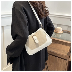 Detail of woven canvas shoulder bag with white leather trim and metal buckle closure