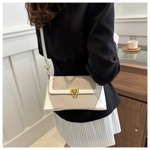 Detail of beige canvas and white leather patchwork crossbody bag with gold U-buckle