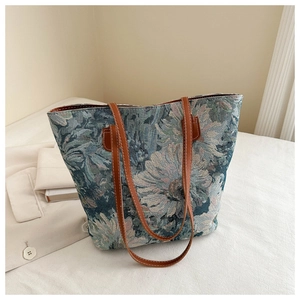 Macro detail of retro teal floral jacquard fabric and brown leather straps on tote bag