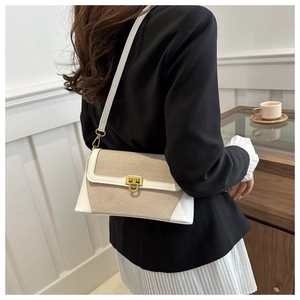 Detail of white leather and beige woven fabric contrast on crossbody bag with gold buckle