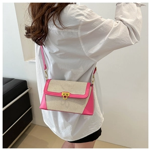Detail view of pink leather trim and gold metal buckle on a beige canvas crossbody bag