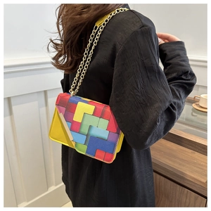 Detail of colorful geometric pattern and golden chain strap on a yellow crossbody bag