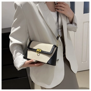 Detail of canvas and leather crossbody bag with elegant gold U-shaped metal buckle