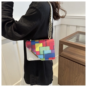 Detail of crossbody bag featuring a colorful tetris pixel pattern and gold chain strap