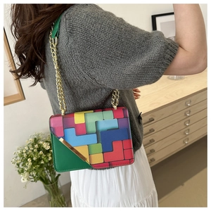 Detail view of colorful geometric flap bag with gold chain and green leather shoulder pad