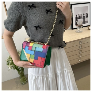 Detail of colorful geometric block pattern shoulder bag with gold chain and metal bar