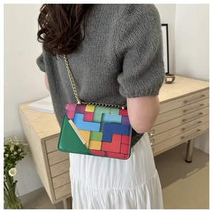 Detail of colorful geometric patchwork crossbody bag with gold chain and metal trim