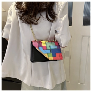 Detail view of a small colorful crossbody bag with geometric patterns and a gold chain strap