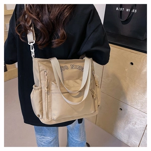 Close-up of khaki tote bag with dual zipper pockets and adjustable wide shoulder strap