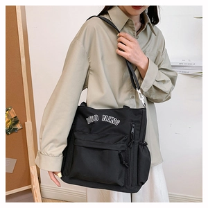 Detail of black canvas tote bag with adjustable strap and white DUO NING logo print