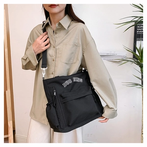 Close-up of black canvas crossbody bag featuring white DUO NING text and multi-pocket design