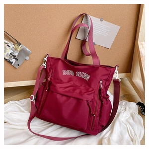 Close-up of burgundy high-capacity tote bag with dual straps and multiple pockets