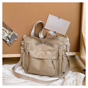 Macro detail of khaki canvas tote with DUO NING logo and functional zipper pockets