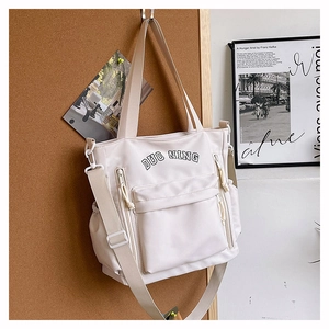 Detail of a large cream tote bag with DUO NING print on a wooden wall hook
