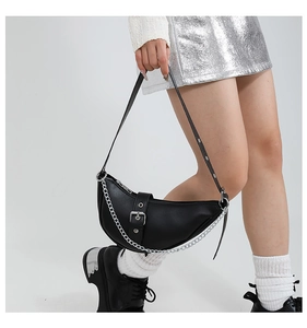Vue latérale du sac demi-lune noir avec chaîne argentée et boucle métallique sur modèle